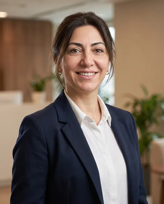 Çıktı: aynı kadın lacivert ceket ve beyaz gömlekle, bulanık ofis önünde gülümseyen kurumsal portre